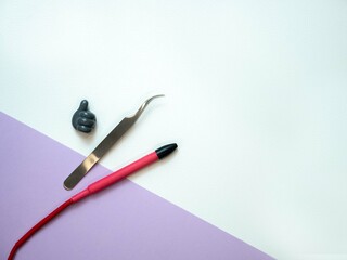 Electroepilation tools and a plastic hand shows a thumbs up on a purple background with space for text. Electric epilator handle, tweezers. Removal of unwanted body hairs