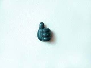 A mockup of a dark gray plastic pen holding a thumb up on a white background with space for text