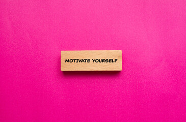 Motivate yourself words written on wooden block with pink background. Conceptual symbol. Copy space.