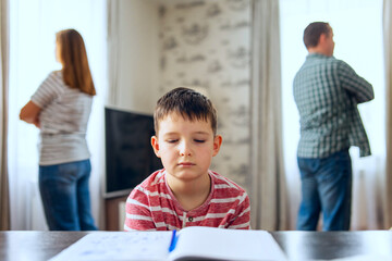 Young Boy Studying with Parents Arguing in Background