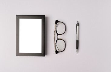 black photo frame; glasses and pen on white background