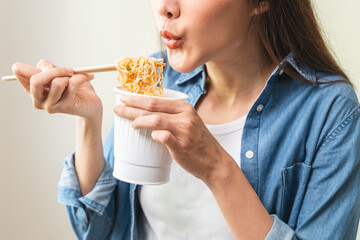 Young female eating instant noodle isolated on background.