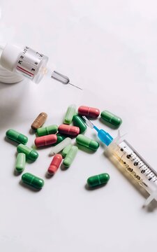 Close-up view of colorful pills and syringe on white, medicine and healthcare concept