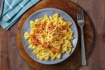 Bolognese pasta in a plate on a round wooden stand next to a fork