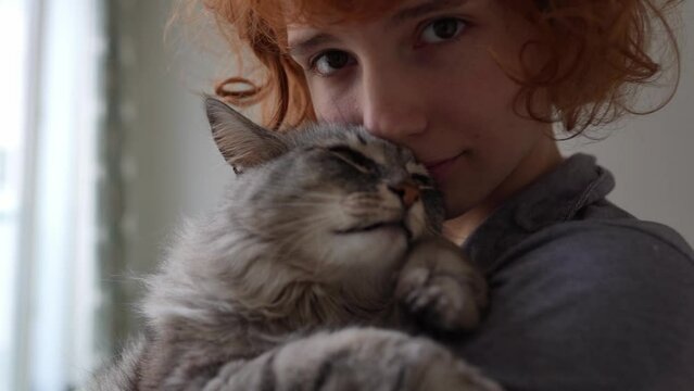 Portrait red-haired curly young woman with beloved fluffy domestic cat
