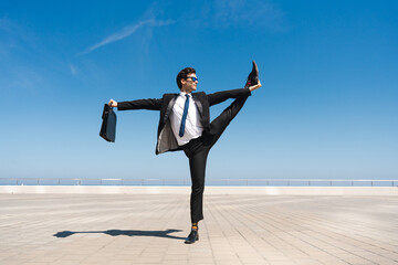 Flexible and cool businessman doing acrobatic trick - obrazy, fototapety, plakaty