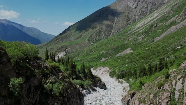 Flight into gorge above river, Kyrgyzstan mountains view. Ala Archa national park near Bishkek. Summer natural landscape, mountain scenery. Popular touristic place for hiking. Aerial drone 4k footage