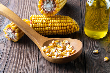 Corn cobs and a bottle of vegetable oil on a wooden table. Corn oil on wooden background.