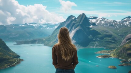 A young woman stands with her back and admires the view of snowy mountains and lake. A traveler traveling on vacation in the most beautiful place in the world. Winter vacation - obrazy, fototapety, plakaty
