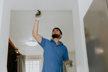 A young man paints the wall with a brush.