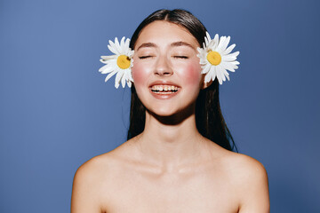 Feminine Beauty: A Young Attractive Woman with Curly Hair, Radiant Skin, and a Happy Smile, Surrounded by Fresh Yellow Gerbera Flowers on a Bright Studio Background