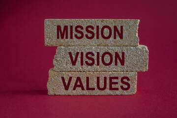 Concept red words Mission Vision Values on brick blocks on a beautiful green table red background. Business mission vision values concept.