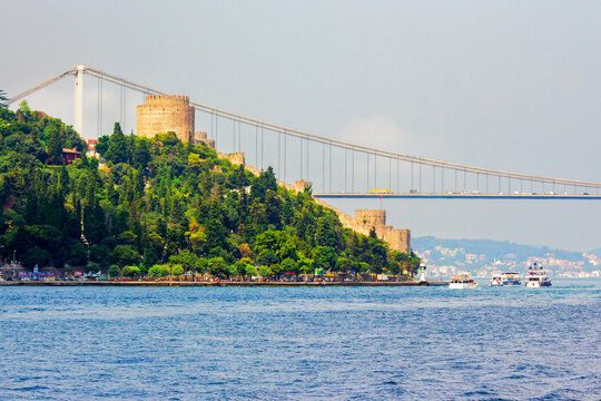 istanbul, turkey - 18 aug 2015: bridge through bosporus. ancient rumelian fortress on the shore in the distance. popular travel destination