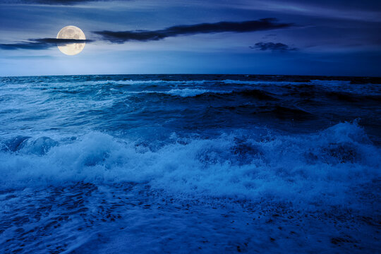 dramatic seascape at night. waves crashing on the beach in full moon light