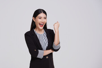 Happy successful Asian business woman in suit smiling pleased looking confident, standing against...