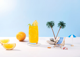 Glass of 100% Orange juice with orange slices fruits on sea beach with white sand. Summer sea vacation and travel concept. Exotic summer drinks.