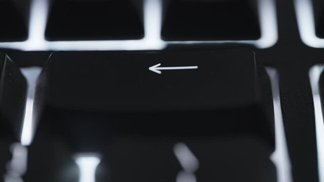Pressing and holding backspace key on black computer keyboard. Close up. 