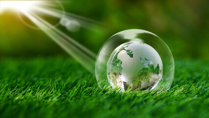Glass earth globe crystal inside of bubble on green grass in the garden background with...