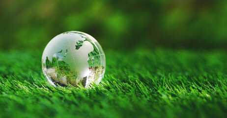 Glass earth globe crystal on green grass in the garden of safe world, save the planet concept,...