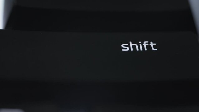 Pressing the shift button on black computer keyboard. Close up. 
