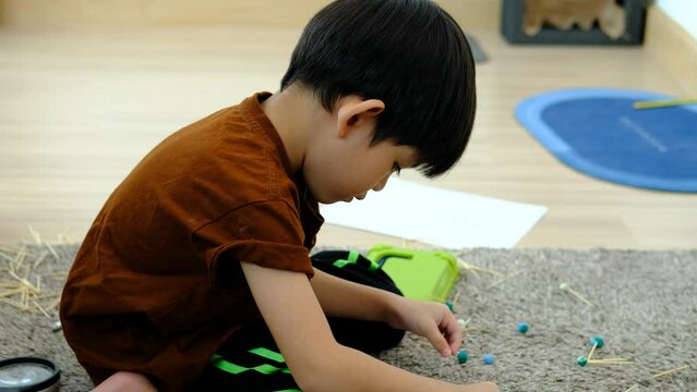 Asian boy playing with plasticine in the room