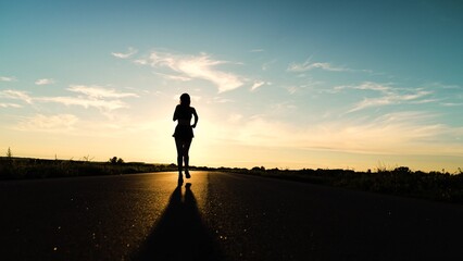silhouette sports girl running along road sunset, mountain trail running, light training, woman...