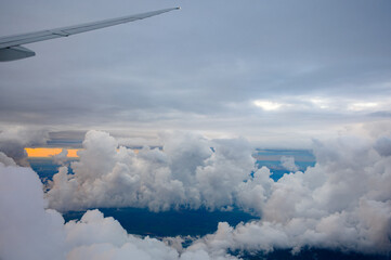 Nuvens laranja e céu azul profundo no final da tarde a partir da janela do avião na região entre...