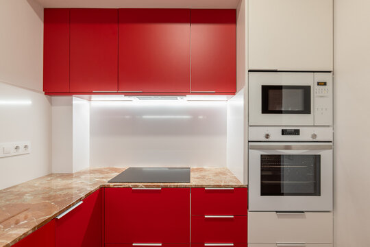 Vibrant red kitchen cabinets with modern appliances and marble countertop