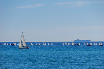 boats in the Mediterranean with a bottom container transporter and small boats and a sailboat