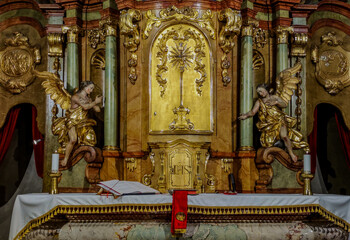 Fototapeta na wymiar Two white burning candles on the Altar in a Catholic Church on Sunday.