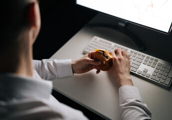Top view unrecognizable businessman eating burger working in office at night. Closeup of...