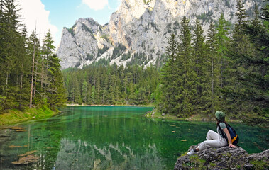 a girl sits on a rock and enjoys nature  on Green lake Styria Austria springtime