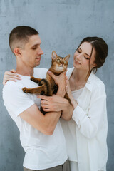 young couple guy and girl in a bright room playing with pets