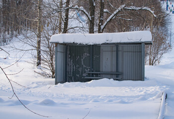 Abandoned snow-covered bus stop in a forest area on a winter day