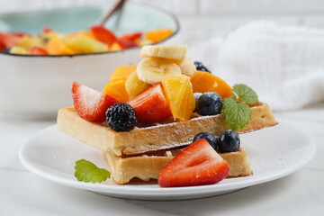 Delicious Belgian waffles with  fresh Summer Fruit salad with oranges, strawberries, blueberries, kiwi and fresh mint.