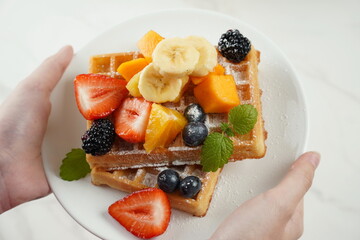 Delicious Belgian waffles with  fresh Summer Fruit salad with oranges, strawberries, blueberries, kiwi and fresh mint.