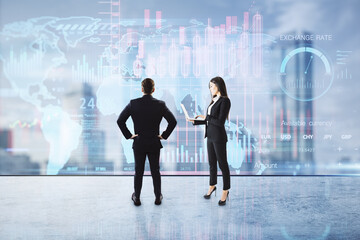 Back view of male with hands on sides and woman with laptop standing on blurry city background with forex chart hologram. Success, finance, teamwork, trade, future concept. Double exposure.