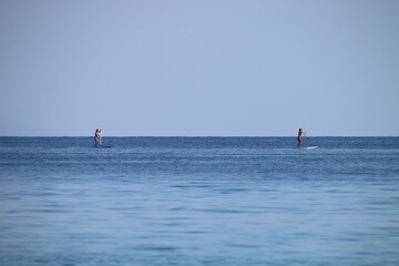 Dos chicas a lo lejos practicando paddle en el océano