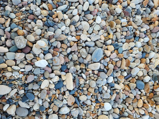 background of colorful pebbles on the lake shore, naturally rounded gravel on the sea shore