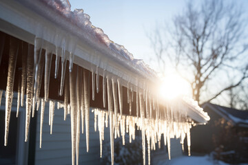 Long icicles hanging from the edge of a roof, glistening in the winter sunlight. Generative AI