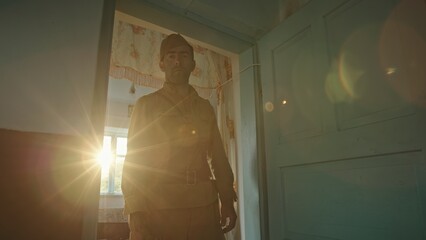 Soldier leaving home and going to war. Tracking shot of man in Soviet soldier uniform putting sack on shoulder and leaving aged house constantly looking back while going to World War II