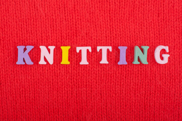 Fototapeta na wymiar Knitting. Knitted Fabric Texture. Word composed from ABC alphabet letters on red background.