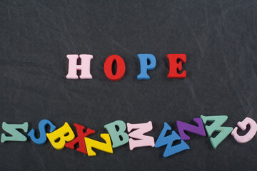 HOPE word on black board background composed from colorful abc alphabet block wooden letters, copy...