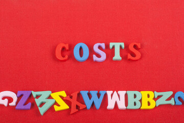 Fototapeta na wymiar costs word on red background composed from colorful abc alphabet block wooden letters, copy space for ad text. Learning english concept.