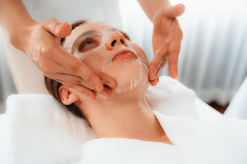Serene modern daylight ambiance of spa salon, woman customer indulges in rejuvenating with facial skincare mask. Facial skin treatment and beauty cosmetology procedure for face. Quiescent
