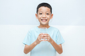 little Asian boy with a glass in his hand of water. shot of a child holding a glass of cold water.