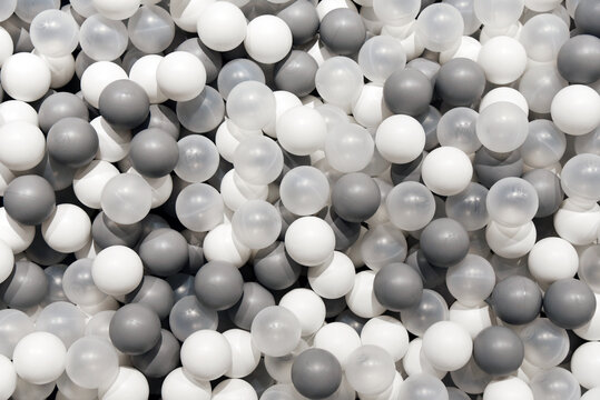 Plastic balls in a dry pool for children, different soft balls gray and white colors background. © Kryuchka Yaroslav