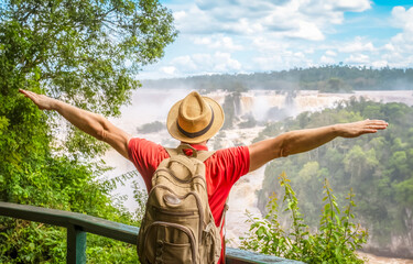 Iguazu Waterfalls, Brazil - Traveler man with raised arms watching Iguacu Falls in Brasil and...