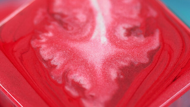 Abstract background. Pigment blend. Colorful spill. Creative glitter white smooth wet substance blot spreading in red ink on square surface edge in macro art.