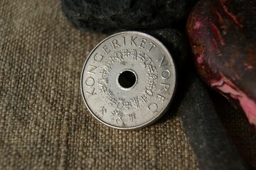 A coin with a hole. Norwegian coin on linen cloth.